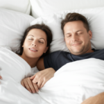 Casal relaxado e feliz na cama após uma noite de sono reparadora