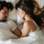 Casal sorrindo e se abraçando na cama.