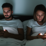 Casal olhando para seus celulares na cama, ignorando um ao outro